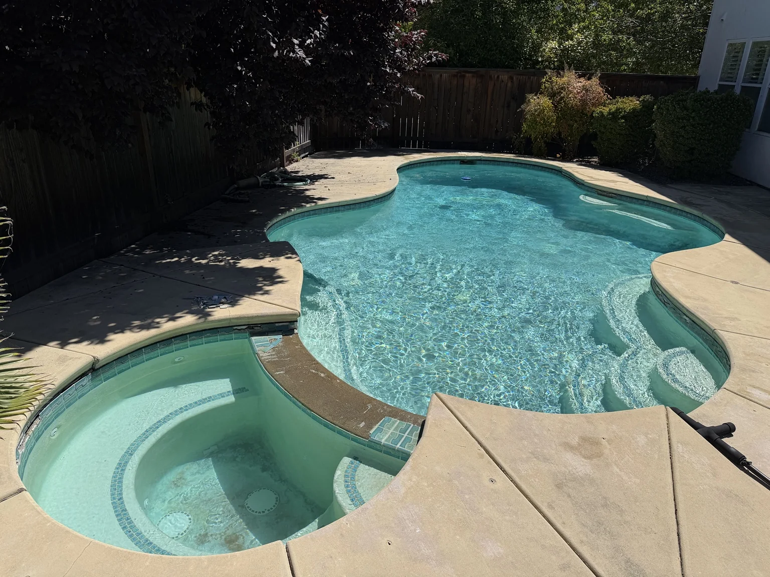 Clear blue residential pool and attached spa after Boyd's Pool Service restoration