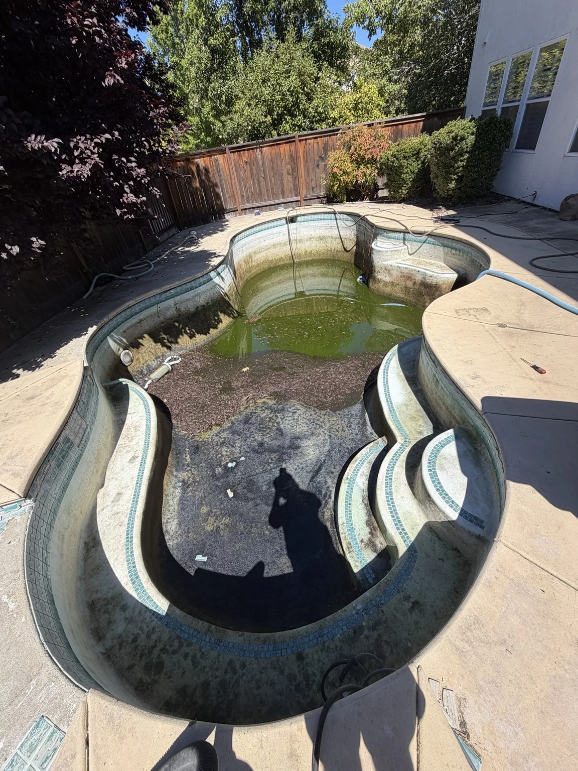 Pool drained down during a major cleanup showing algae and buildup on the surfaces